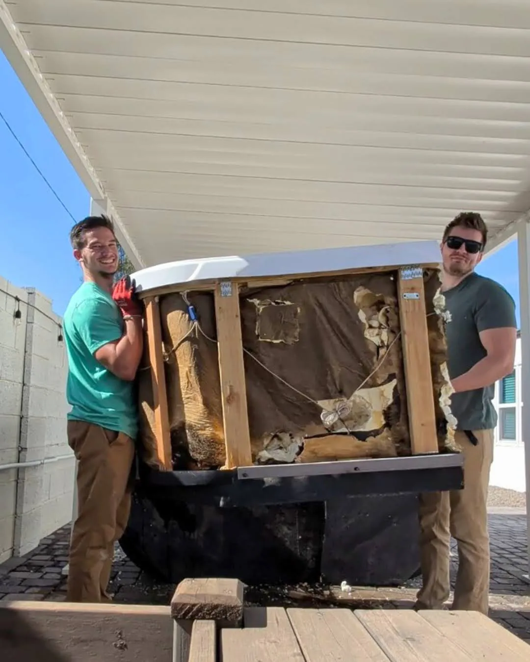 Crew supporting a hot tub section during covered-patio removal in Phoenix