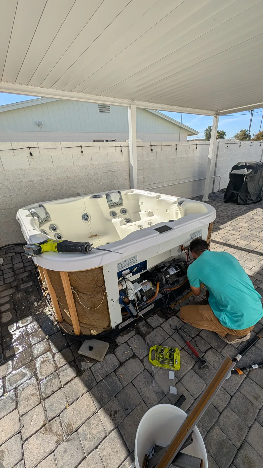 Hot tub dismantling underway beneath a covered patio in Phoenix