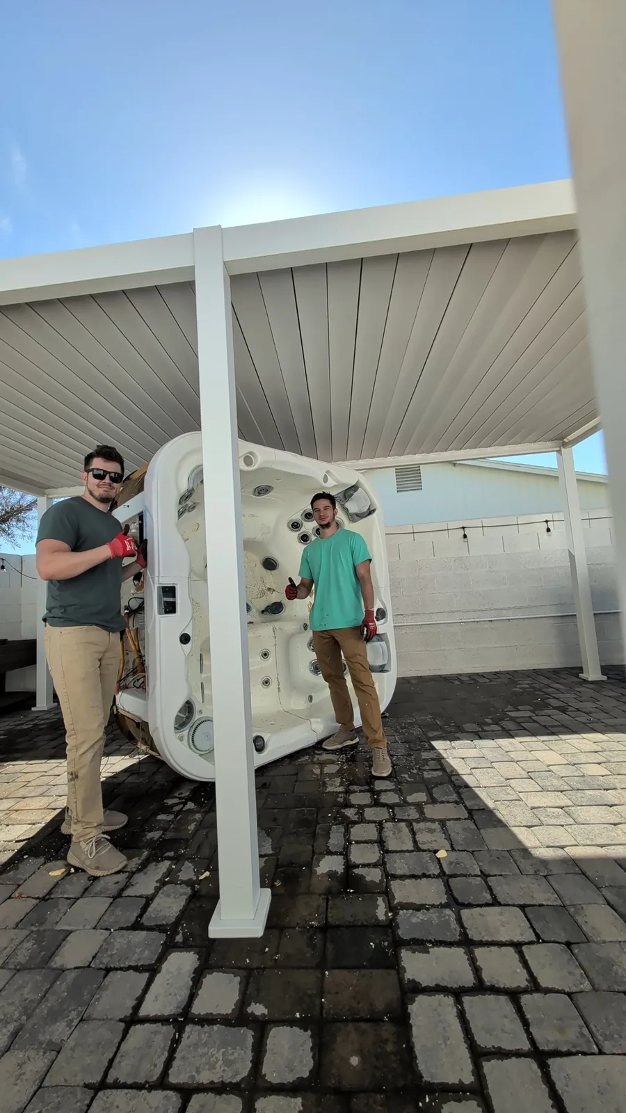 Reset crew moving a hot tub shell beneath a covered patio in Phoenix
