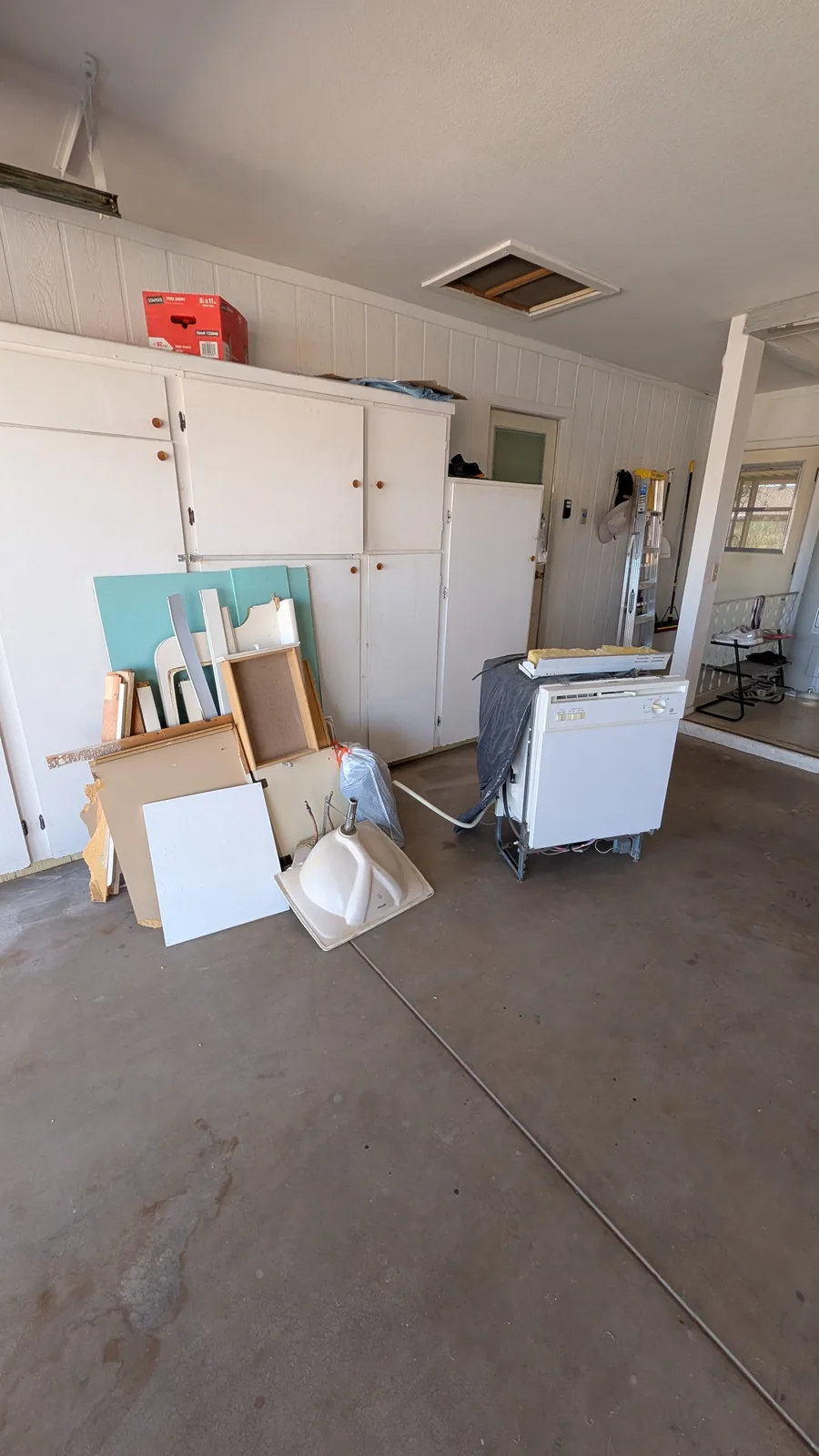Dishwasher, cabinet pieces, and renovation debris staged in a Sun City garage