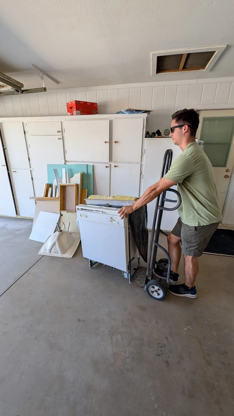 Dishwasher being moved with a hand truck during garage debris removal