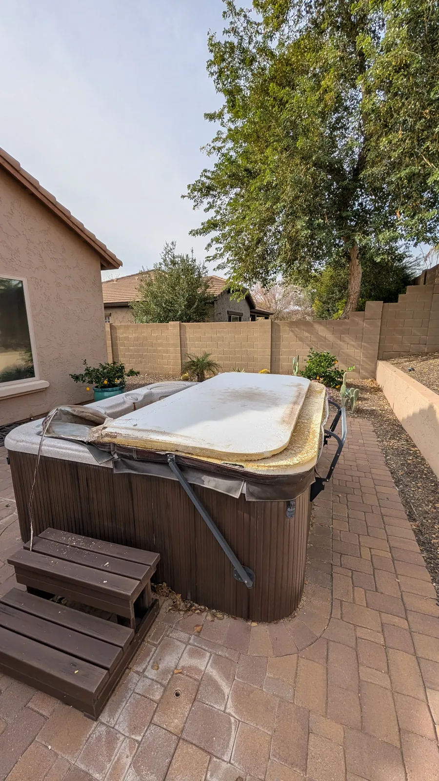 Intact hot tub on a paver patio before dismantling in North Phoenix
