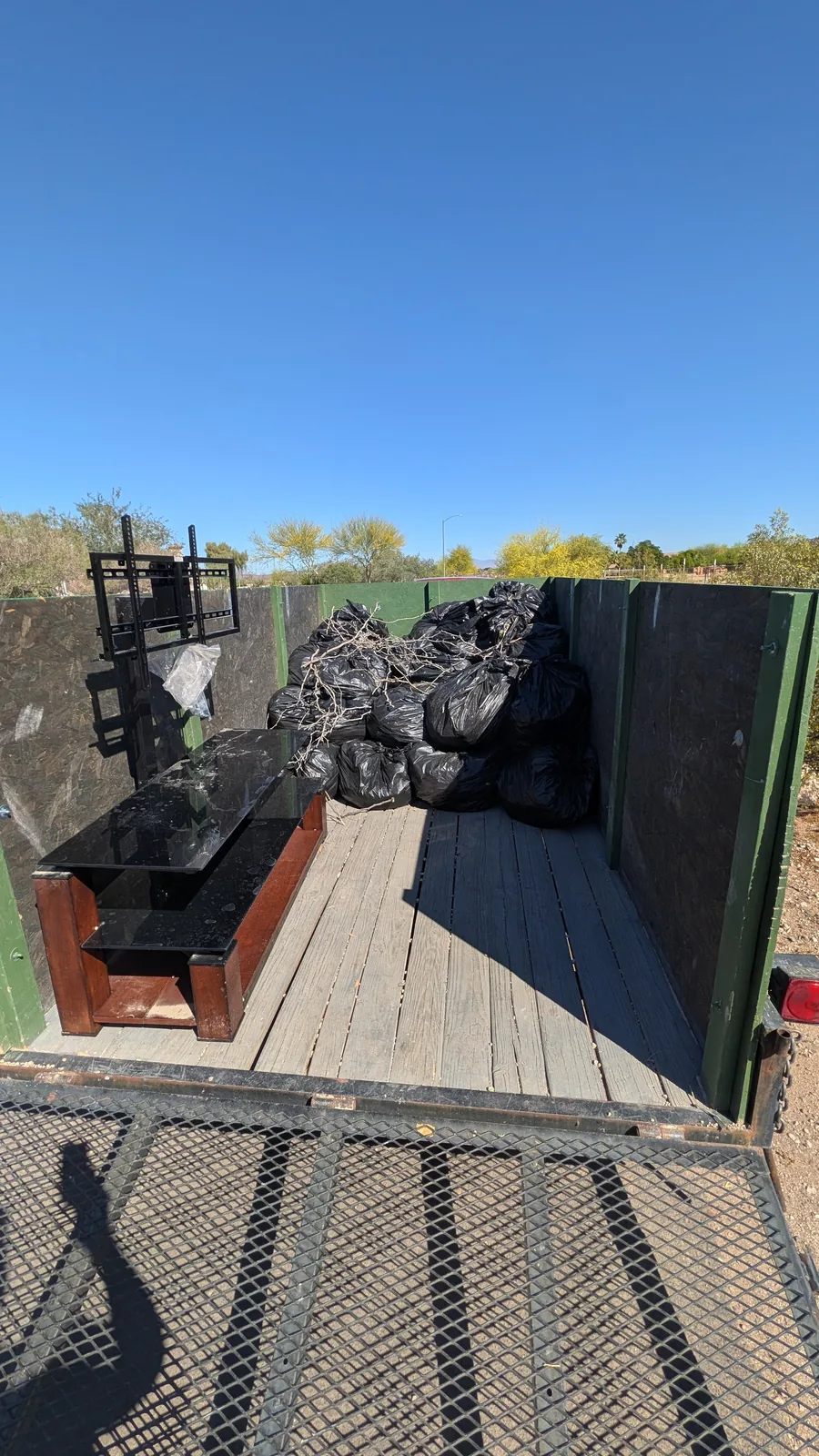 Bagged debris, branches, and a TV stand in a Peoria junk removal trailer