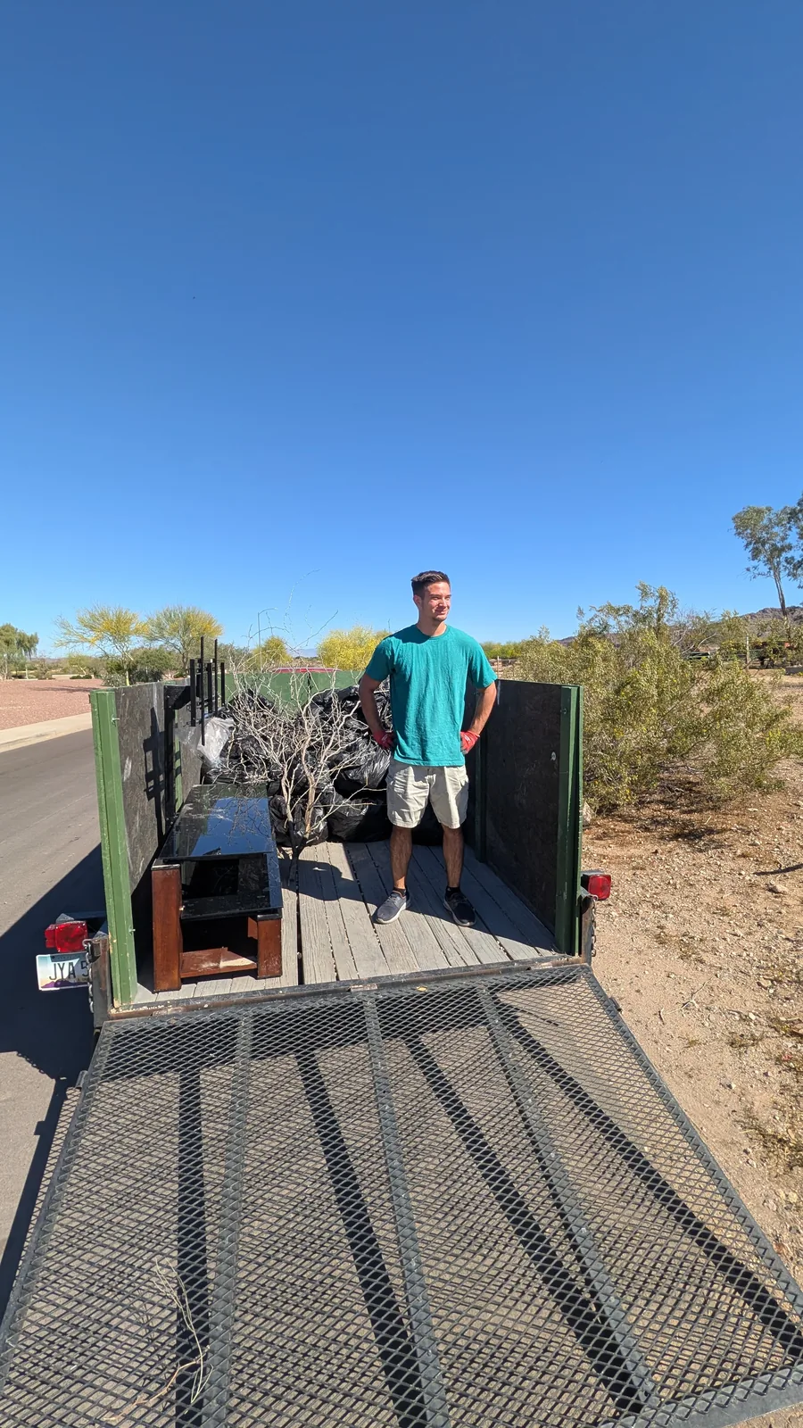 Crew member organizing mixed yard and household junk in the trailer