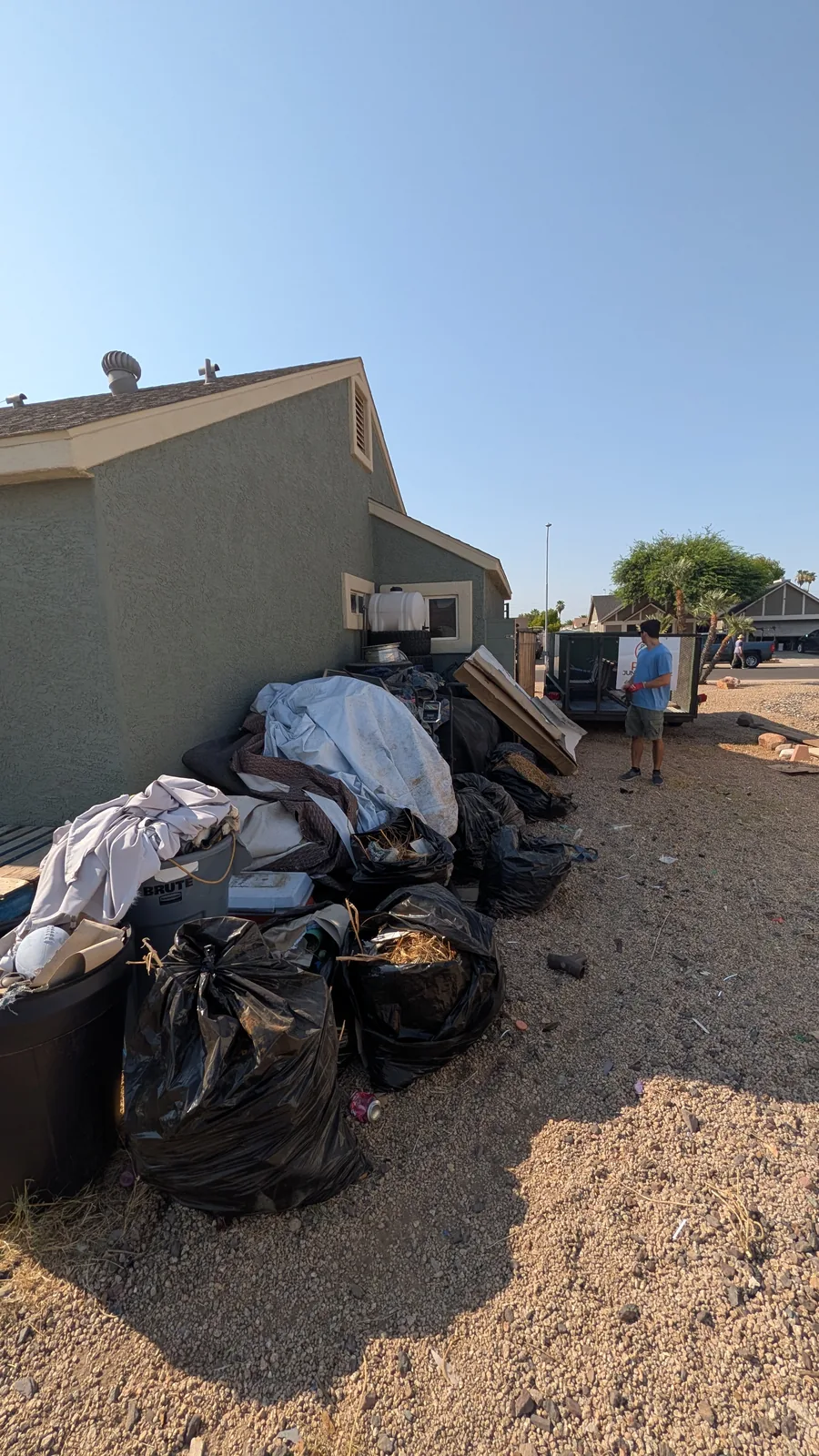 Crew member working beside a large side-yard junk pile in Peoria